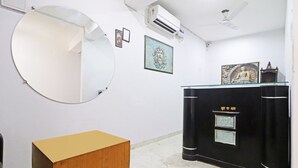 Ein Zimmer mit einem runden Spiegel, einer Holzkabine, einer schwarzen Theke mit Dekoration und einem Deckenventilator.