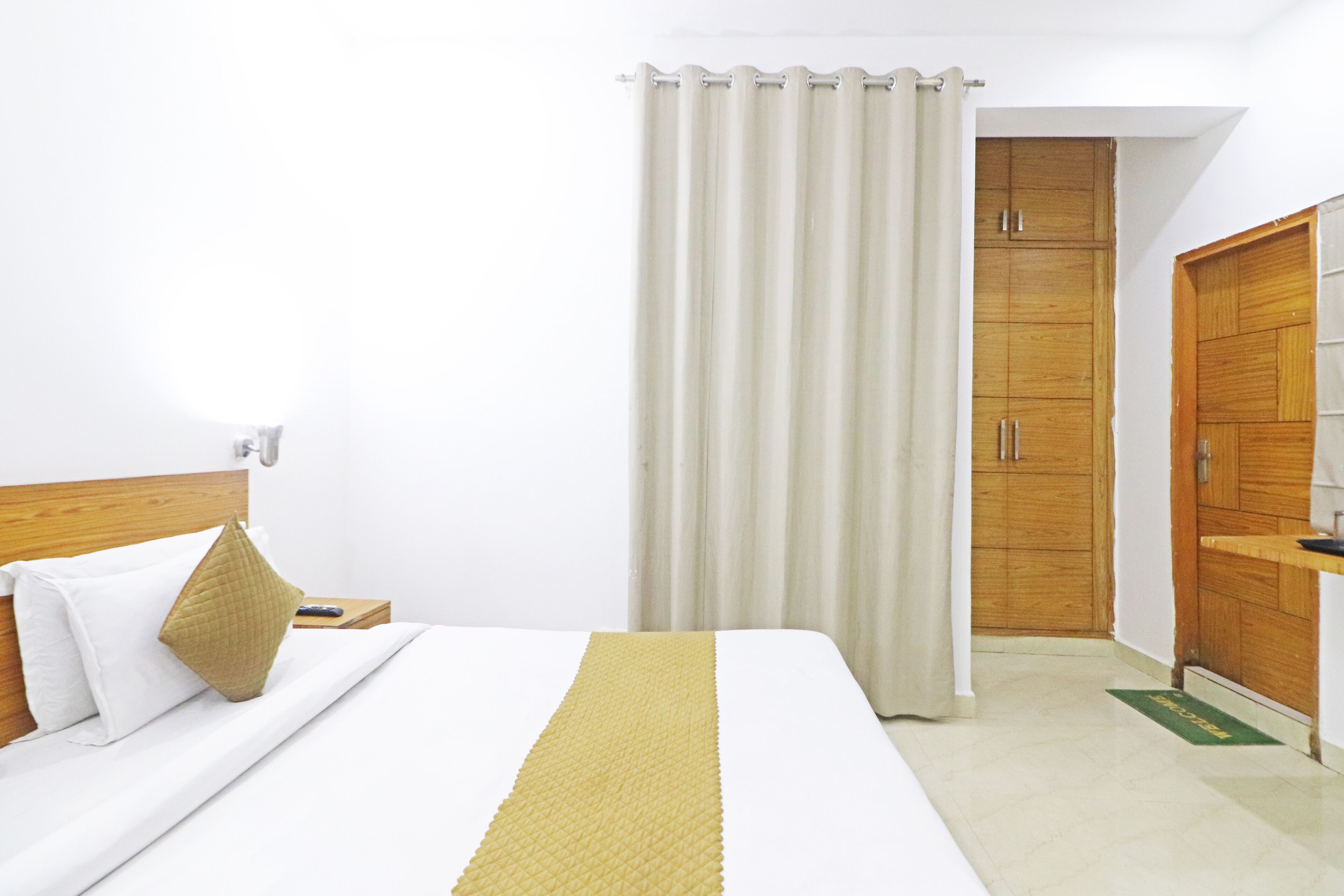 Habitació d'hotel amb un llit, un armari de fusta i un estri de porta verd.