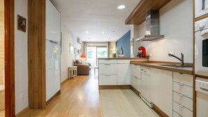 Una cucina moderna con mobili bianchi, pavimento in legno e un elettrodomestico rosso.