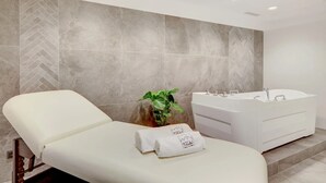 Un baño moderno con una bañera grande, una silla de masajes y una planta en maceta.