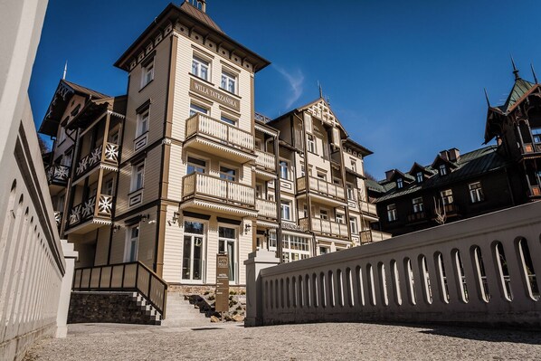A multi-story hotel with a classic architectural style, featuring balconies and a prominent entrance with steps. - Hotel Willa Tatrzańska (Krynica-Zdroj)