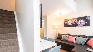 En trappa som leder upp till ett vardagsrum med en soffa, ett bord och en lampa.