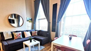 A modern living room with a dark sofa, a white coffee table, and a dining table with red chairs. - Bright charming - great central location Fast WIFI (Dublin 1)