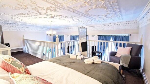 A bedroom with a large bed, a balcony with blue curtains, a chair, and a TV. - Bright charming - great central location Fast WIFI (Dublin 1)
