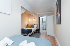 A modern bedroom with a bed, a small table, and a bathroom visible through an open door. - Lovely Spacious Apartment Right in City Centre! (Dublin 1)