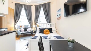 Un dormitorio moderno con cama, mesita de noche y televisor montado en la pared.