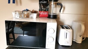 Une cuisine équipée d’un four à micro-ondes, d’un grille-pain, d’une machine à café et d’un paquet de café.
