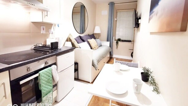 A compact living space with a kitchenette, a sofa, a dining table, and a large mirror. - Cosy Studio right in city centre (Dublin 1)