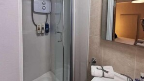 Un baño moderno con ducha de vidrio, lavamanos blanco y espejo superior.