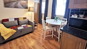 Un espacio habitable compacto con sofá, mesa de comedor, sillas y una zona de cocina.