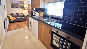 Cocina compacta con lavadora, lavaplatos y ventana con persianas.