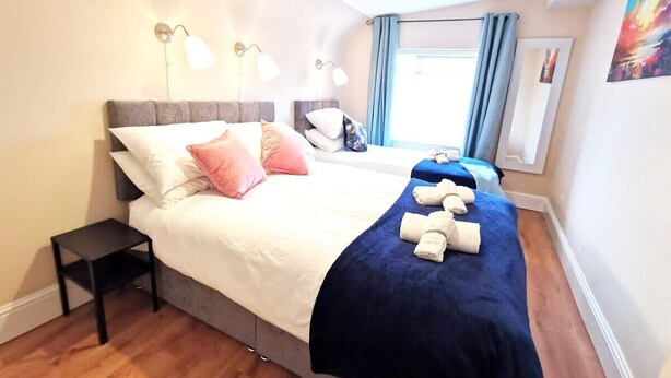 Ett hotellrum med en stor säng, sänglampor, ett litet bord och ett fönster med gardiner.