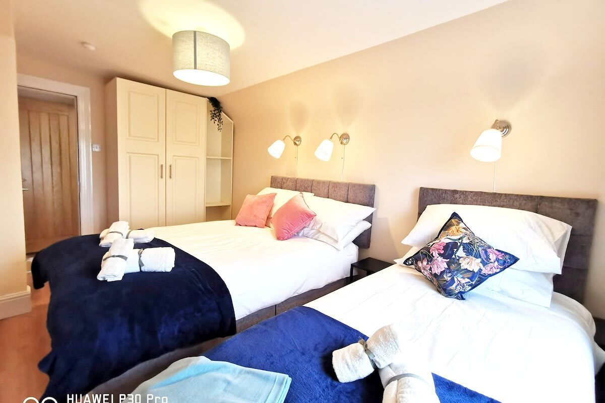 Een hotelkamer met twee bedden, elk met hoofdbord, een kledingkast en wandlampen.