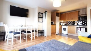 Ett kompakt bostadsutrymme med matplats, kök och en soffa.