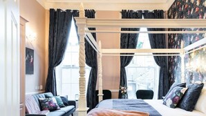 Un dormitorio con cama con dosel, un sofá y una araña.