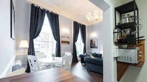 Una sala de estar moderna con un sofá, una mesa de comedor con sillas y una zona de cocina con microondas y estanterías.