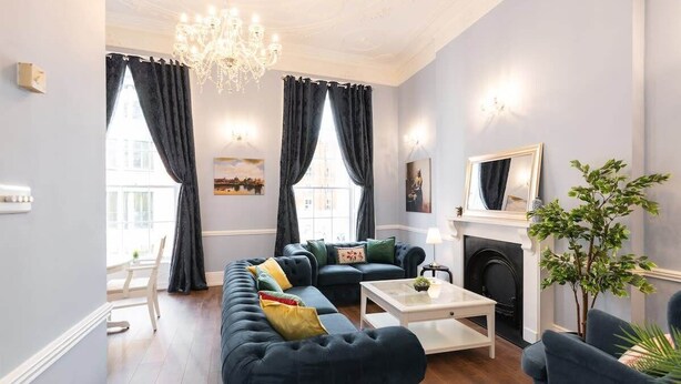 Una sala de estar con un sofá azul oscuro, una mesa de centro blanca y una chimenea.