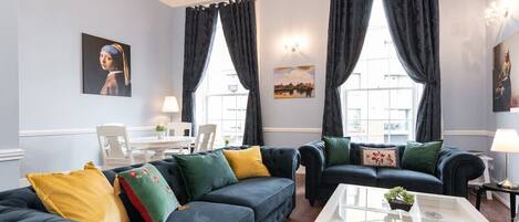 A living room with two dark sofas, a white coffee table, and a chandelier.