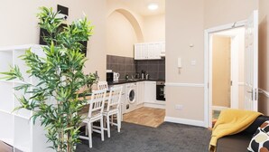 Une cuisine compacte avec des meubles blancs, un lave-linge et un coin repas comprenant une table et des chaises.