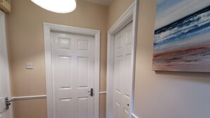Un corridoio con due porte bianche, pareti color beige e un quadro sulla parete destra.