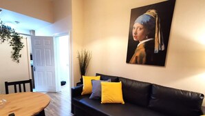 A living room with a black sofa, wooden dining table, and a painting on the wall. - Central 1bed apartment with reliable fast WIFI (Dublin 1)