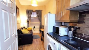 A compact kitchen with a washing machine, a microwave, and wooden cabinets. - Central 1bed apartment with reliable fast WIFI (Dublin 1)