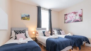 Une chambre d’hôtel avec deux lits, une fenêtre avec des rideaux et un tableau au mur.