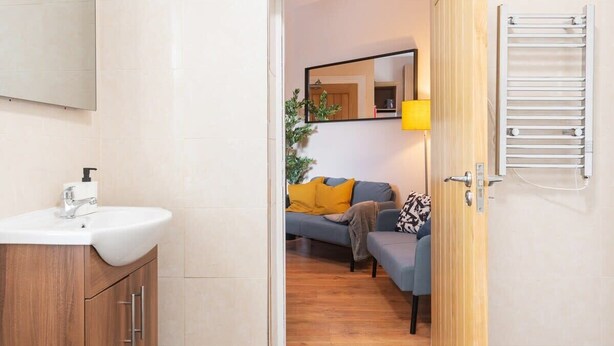 Une salle de bain moderne avec un meuble-lavabo en bois, un lavabo blanc et un miroir.