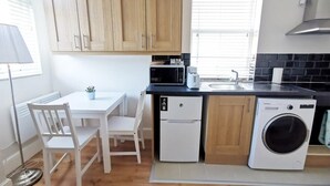 A compact kitchen with wooden cabinets, a microwave, a toaster, a sink, and a washing machine. - Cosy studio new renovated - kitchen, TV &Fast WIFI (Dublin)