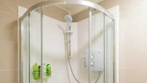 Een moderne badkamer met een douchecabine van glas, een witte wastafel en een glazen deur.