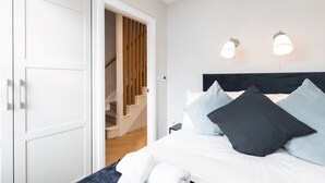 Een slaapkamer met een bed, een witte inbouwkast en een trap naar een houten deur.