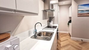 Een moderne keuken met witte kasten, een roestvrijstalen spoelbak en een inbouw afzuigkap.