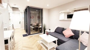 Een moderne woonkamer met een bank, salontafel en een eethoek met een tafel en stoelen.