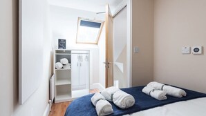 Una camera da letto con un letto, un armadio, uno scaffale con articoli da toilette e un lucernario.