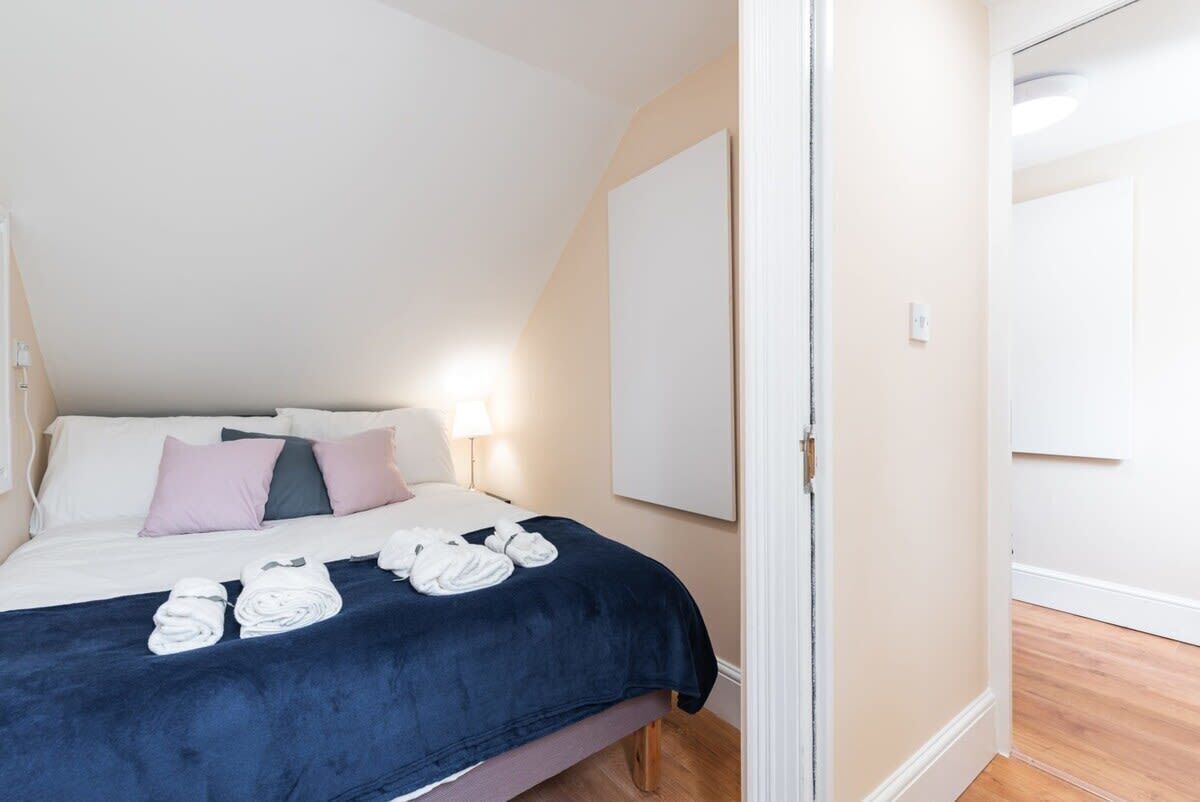 Ein ordentlich gemachtes Bett mit Kissen, einer blauen Decke und zusammengerollten Handtüchern.