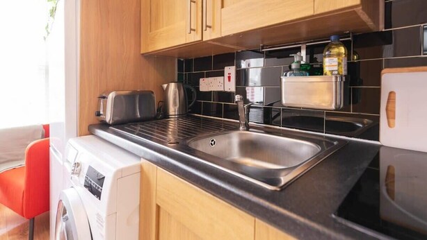A compact kitchen with wooden cabinets, a stainless steel sink, a built-in toaster, and a washing machine. - *COSY 2BED APARTMENT*FAST WIFI*&TV*TRENDY RANELAGH (Dublin 6)