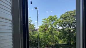 A view from a window overlooking a parking area with a body of water, trees, and a street lamp. - Navigli bilocale  (Milan)