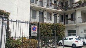 A multi-story residential building with balconies, a no parking sign, and a gated entrance. - Navigli bilocale  (Milan)