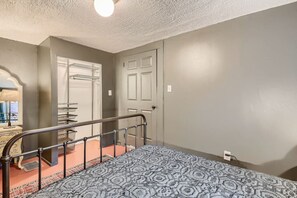 Cozy retreat with a single bed, metal railing, and a small table with a lamp.