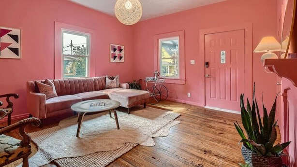 Un salon décoré dans des tons roses, avec un canapé, une table basse ronde et un vélo.
