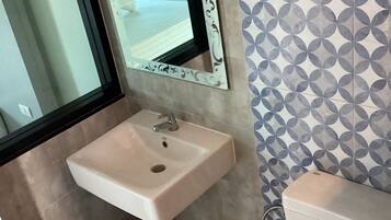 Un baño con lavamanos, inodoro y espejo.