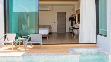 Ein modernes Hotelzimmer mit Glastür zu einem Balkon, einem Bett, einem Schreibtisch und einer Duschkabine.
