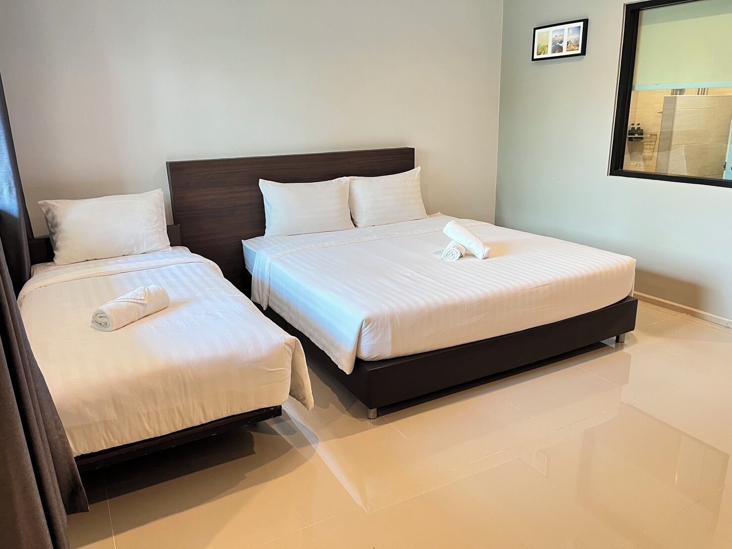 A hotel room with two beds, a dark headboard, and a large window.
