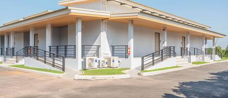 Un edificio con vestíbulo cubierto, unidades de aire acondicionado exteriores y una escalera que conduce a la entrada.