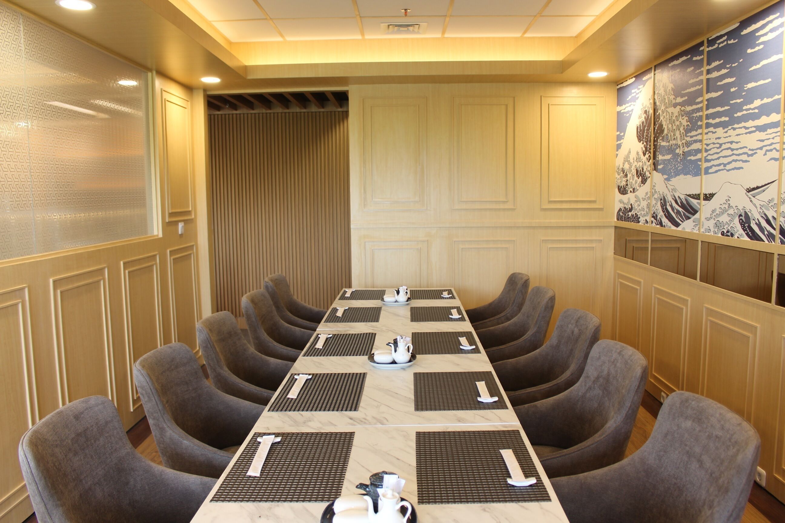 A conference room with a long table, multiple chairs, and a decorative wall.