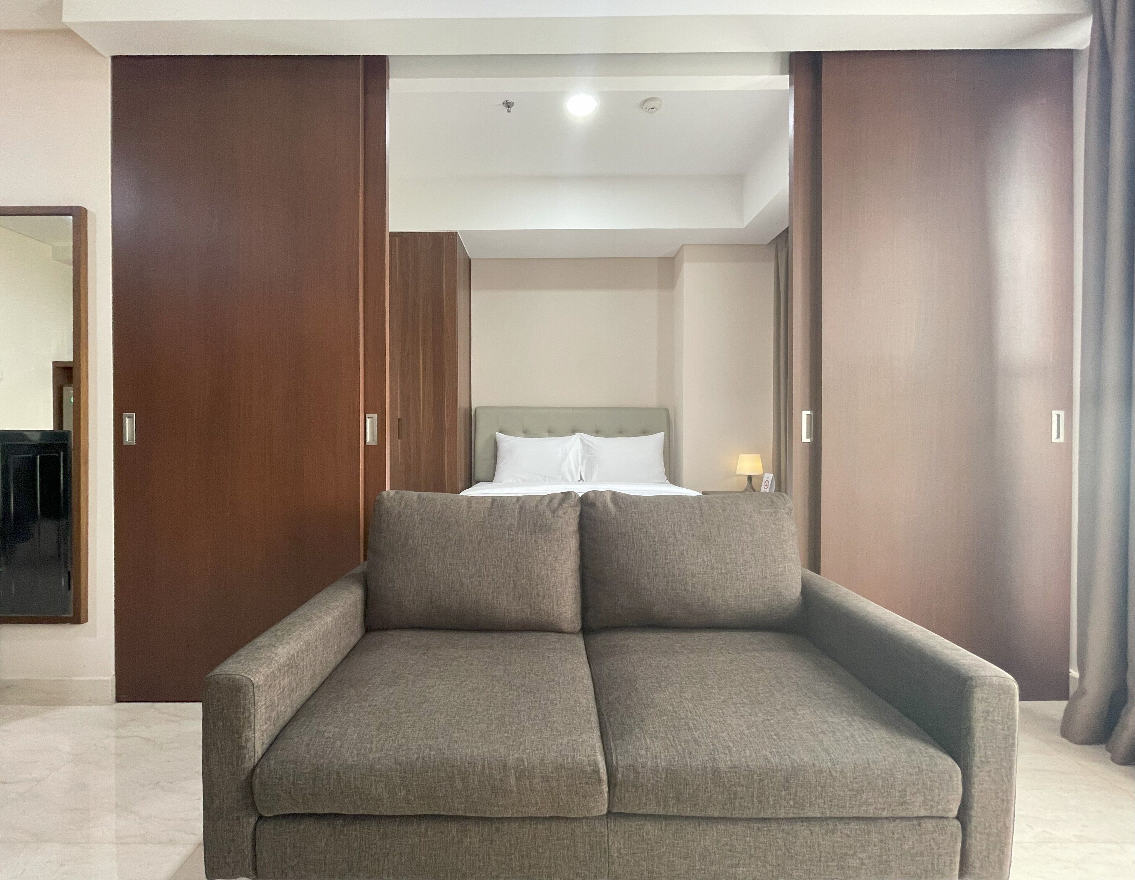 Ein modernes Schlafzimmer mit Schlafsofa, großem Kleiderschrank und Nachttisch mit Lampe.