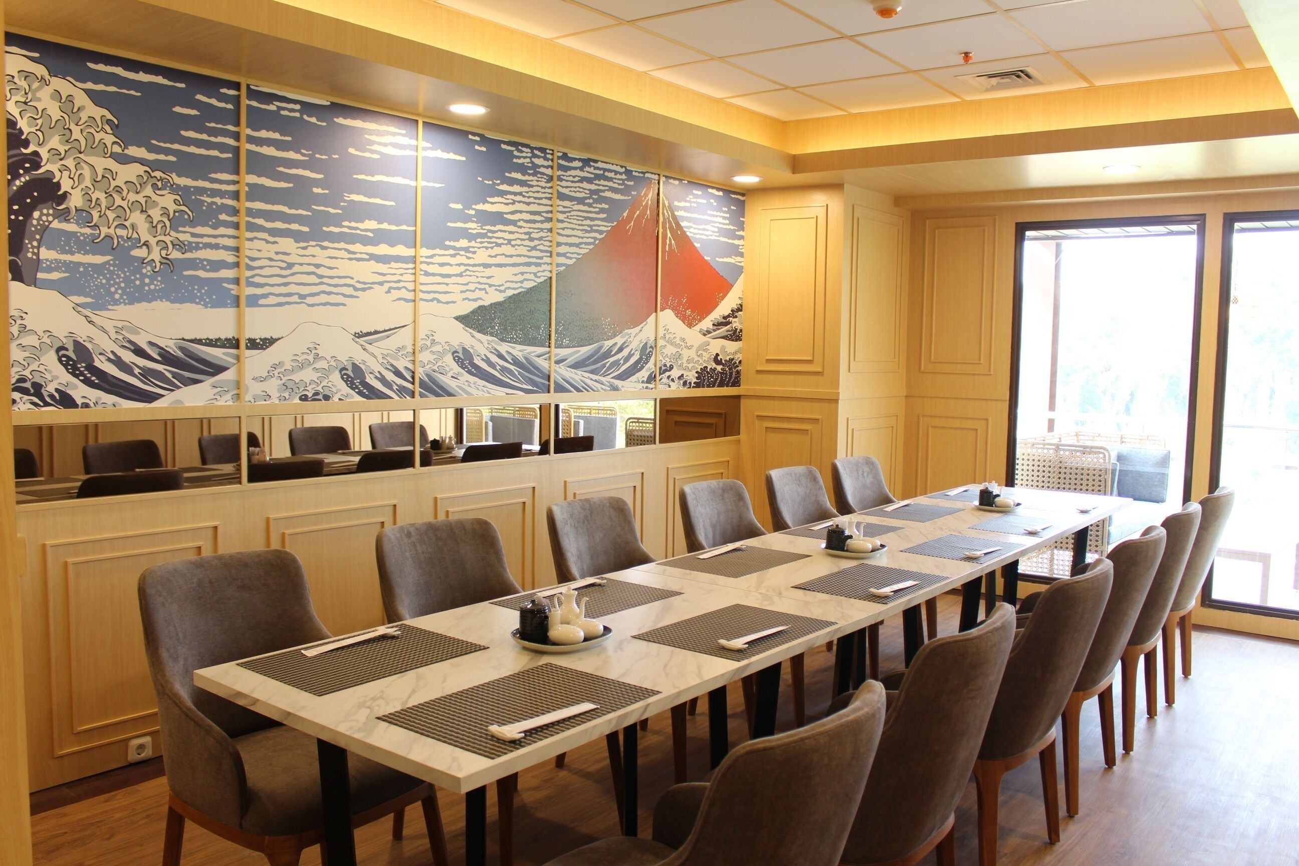 A conference room with a long table, chairs, and a large Japanese wave painting on the wall.