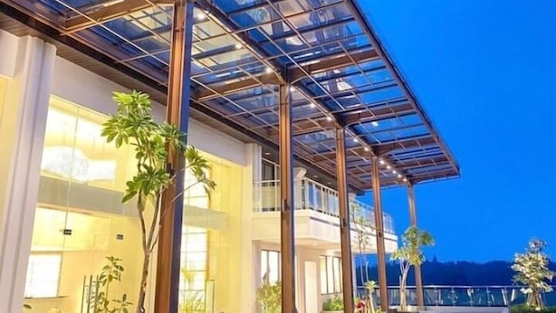 Un edificio moderno con fachada de vidrio, terraza al aire libre y piscina.