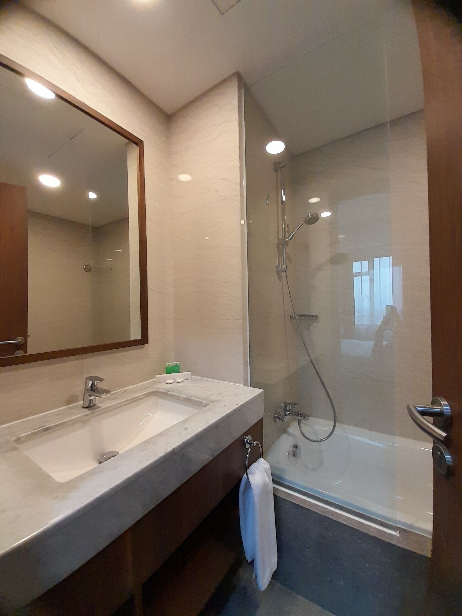 A modern bathroom with two sinks, a large mirror, and a glass-enclosed shower area.