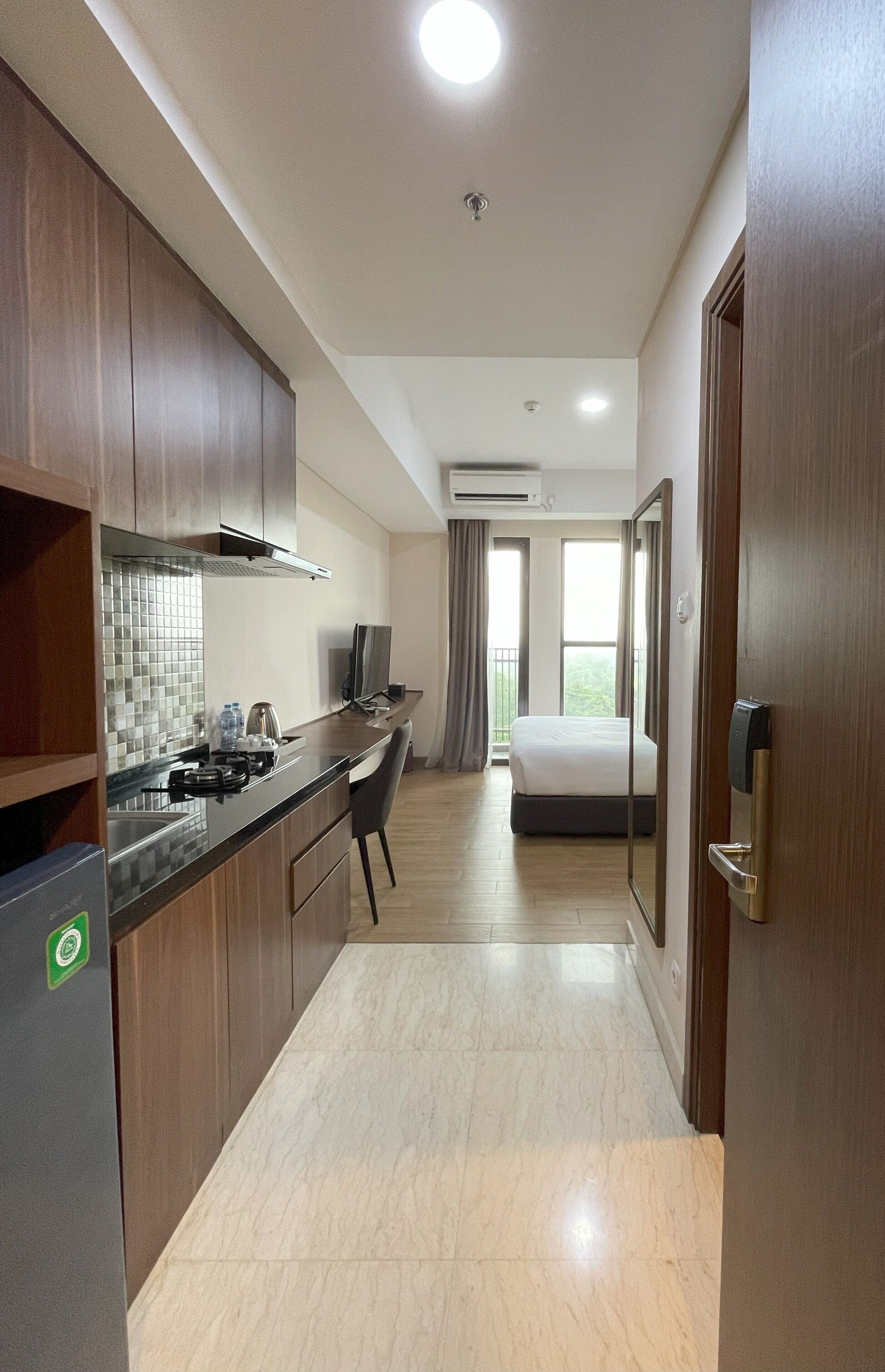 Una camera d'albergo con angolo cottura, un letto e un bagno.